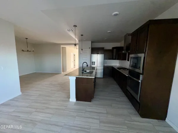 a large kitchen with wooden floor and stainless steel appliances