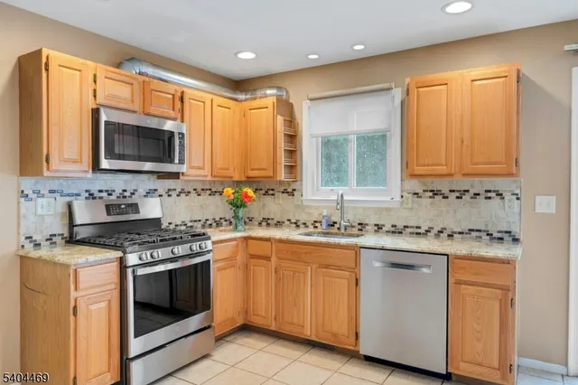 a kitchen with stainless steel appliances granite countertop a stove top oven a sink dishwasher and a refrigerator