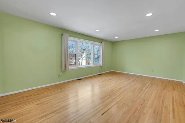 an empty room with wooden floor and window