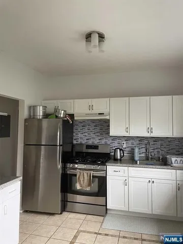 a kitchen with a stove a refrigerator and white cabinets
