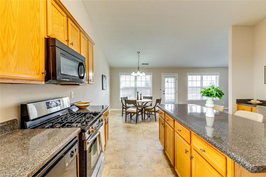 5602 Swanson Road Ellenwood, GA 30294 - Photo 14 of 36 a kitchen with stainless steel appliances granite countertop a stove top oven a sink a dining table and chairs with wooden floor