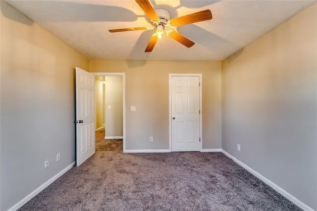 an empty room with closet and a chandelier fan