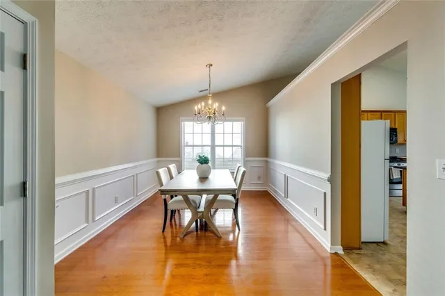 a dining room with chandelier and wooden floor