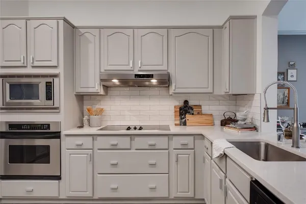 a kitchen with granite countertop white cabinets and stainless steel appliances