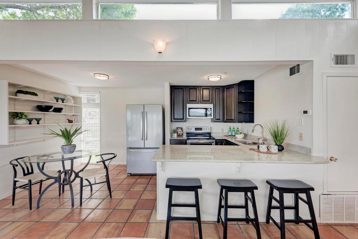8130 Joy Road Volente, TX 78641 - Photo 15 of 36 Kitchen featuring open shelves, stainless steel appliances, a kitchen breakfast bar, a peninsula, and light stone countertops