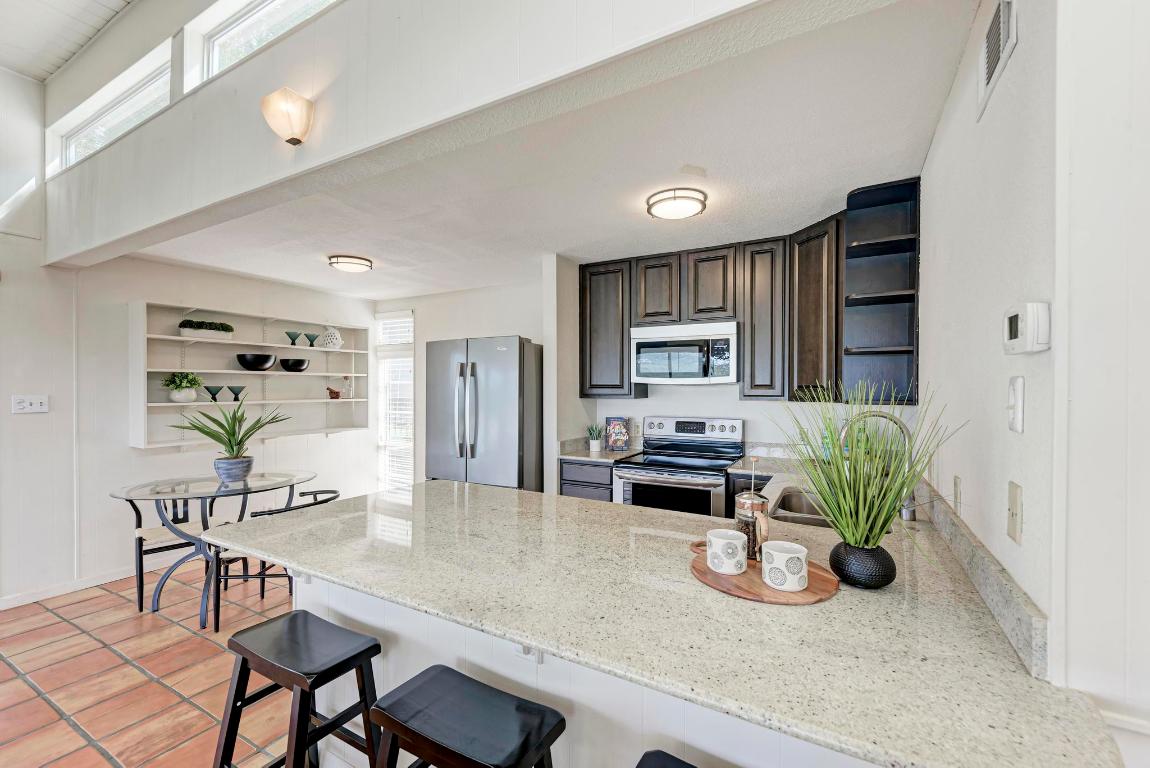 8130 Joy Road Volente, TX 78641 - Photo 16 of 36 Kitchen with open shelves, a peninsula, appliances with stainless steel finishes, a breakfast bar, and dark brown cabinetry