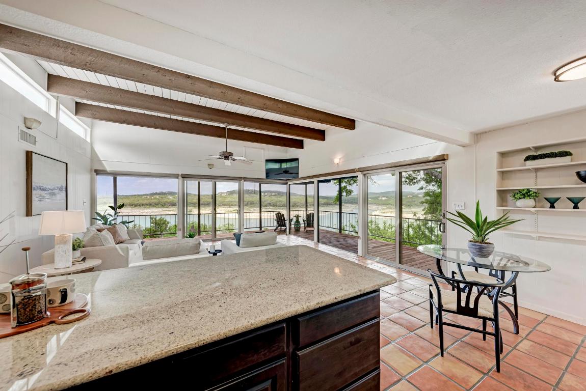 8130 Joy Road Volente, TX 78641 - Photo 18 of 36 Kitchen featuring dark brown cabinets, light stone counters, light tile patterned floors, beamed ceiling, and a ceiling fan