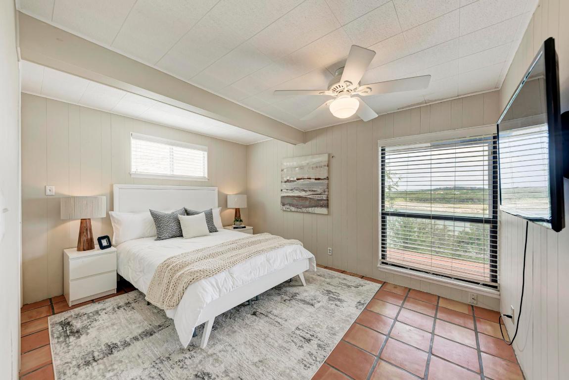 8130 Joy Road Volente, TX 78641 - Photo 20 of 36 Bedroom with wood walls, tile patterned floors, and ceiling fan