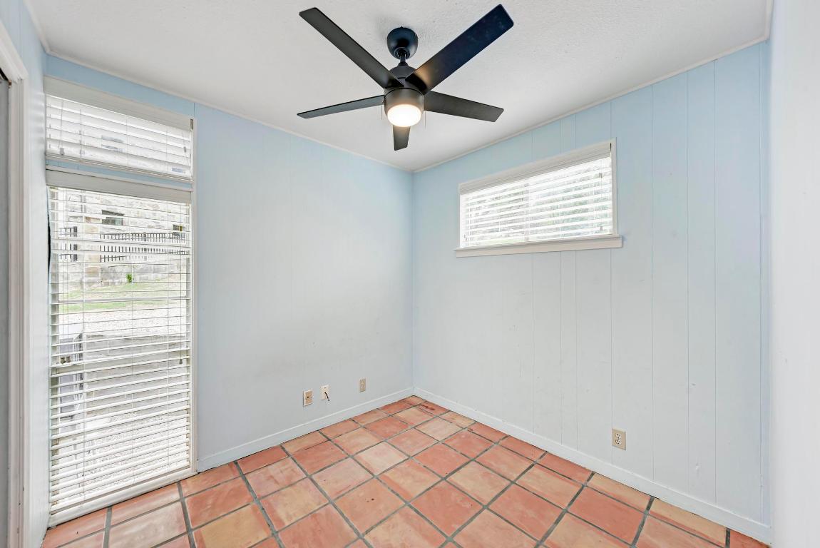 8130 Joy Road Volente, TX 78641 - Photo 24 of 36 Tiled spare room featuring a ceiling fan and wooden walls