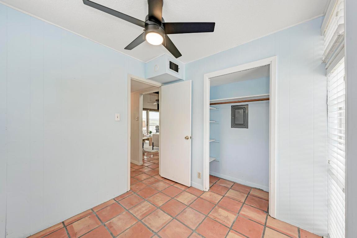 8130 Joy Road Volente, TX 78641 - Photo 25 of 36 Unfurnished bedroom featuring a ceiling fan, a closet, electric panel, light tile patterned floors, and multiple windows