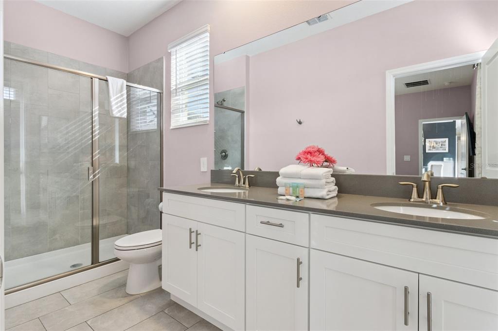 4378 Rhyme Street Kissimmee, FL 34746 - Photo 21 of 41 a bathroom with a granite countertop sink a toilet and a shower