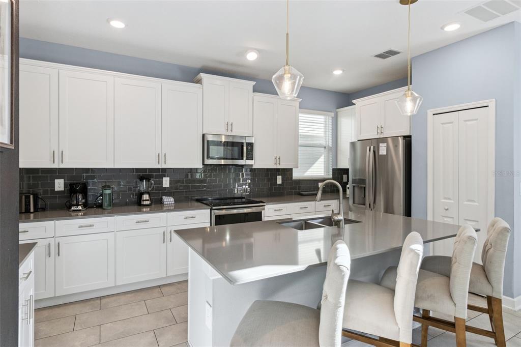 4378 Rhyme Street Kissimmee, FL 34746 - Photo 8 of 41 a kitchen with white cabinets and stainless steel appliances
