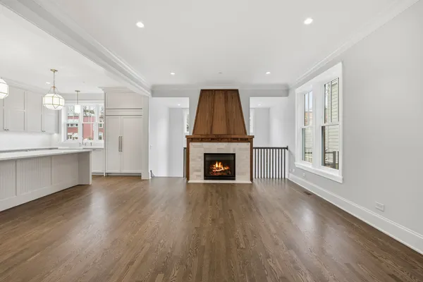 a view of an empty room with wooden floor fireplace and a window