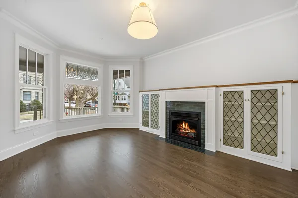 a view of an empty room with wooden floor fireplace and a window