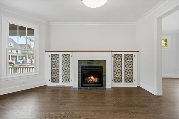 a view of an empty room with wooden floor fireplace and a window