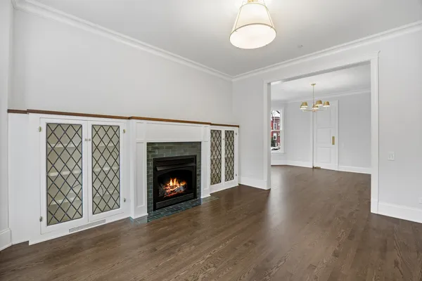 an empty room with wooden floor fireplace and windows
