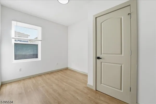 an empty room with wooden floor closet and windows