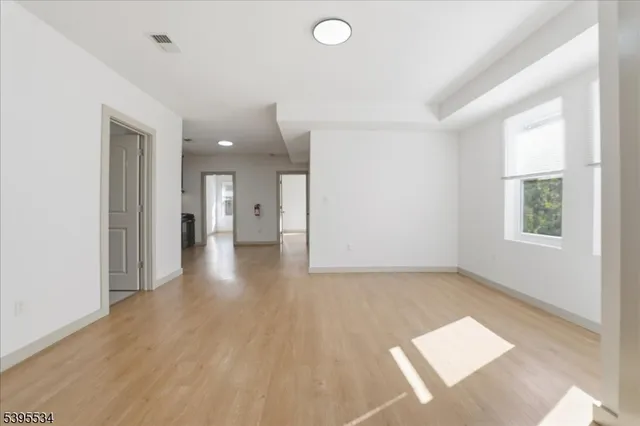 a view of a hallway with wooden floor and a living room