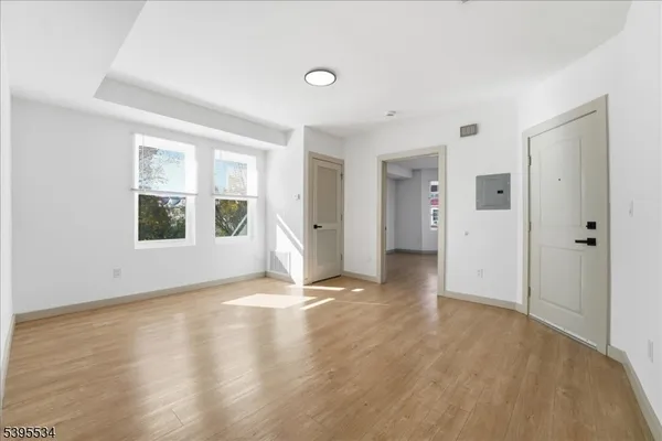 a view of an empty room with window and wooden floor