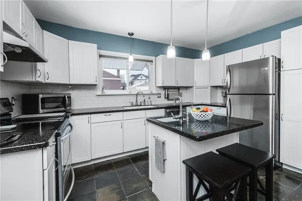 a kitchen with stainless steel appliances granite countertop a sink a stove and cabinets