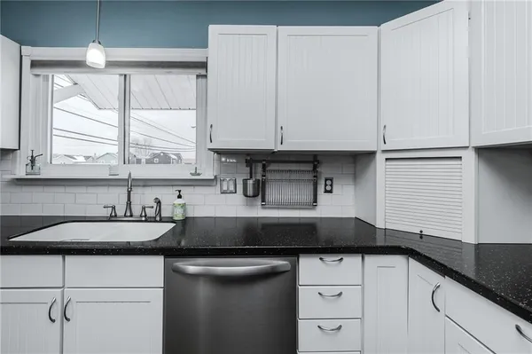 a kitchen with stainless steel appliances granite countertop a sink a stove a refrigerator cabinets and chairs