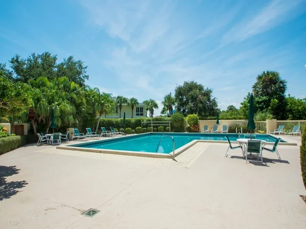a view of swimming pool with seating area and trees in the background