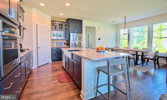 19209 Cavendish Way Lewes, DE 19958 - Photo 3 of 6 a kitchen with stainless steel appliances a dining table chairs and a wooden floor
