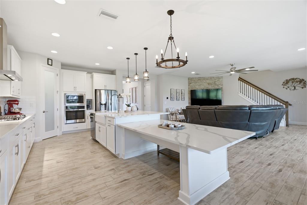 12970 Steed Trce Loop Lithia, FL 33547 - Photo 13 of 57 a kitchen with stainless steel appliances kitchen island granite countertop a sink a stove and a wooden floors