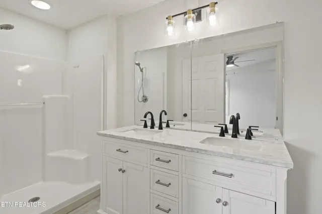 a bathroom with a granite countertop sink a toilet a mirror and shower