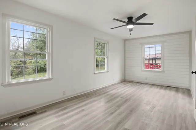 a view of empty room with wooden floor and fan
