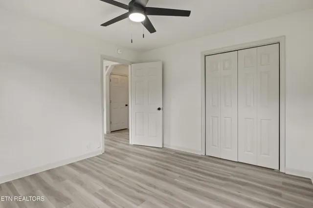 an empty room with wooden floor closet and windows