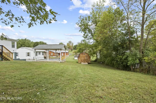 a view of a big house with a big yard and large trees