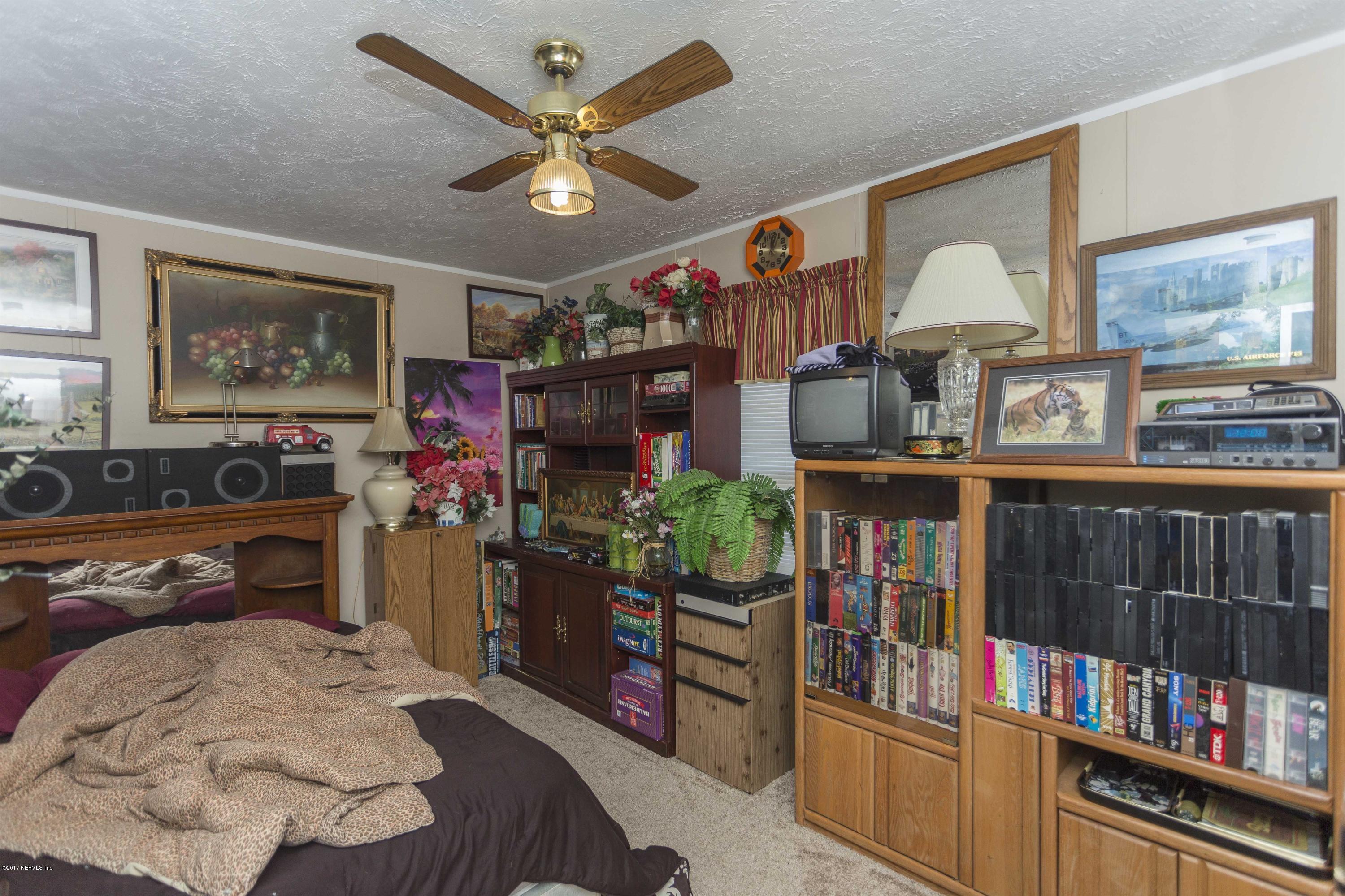 4049 Bronco Road Middleburg, FL 32068 - Photo 17 of 21 a bedroom with furniture a flat screen tv and a book shelf