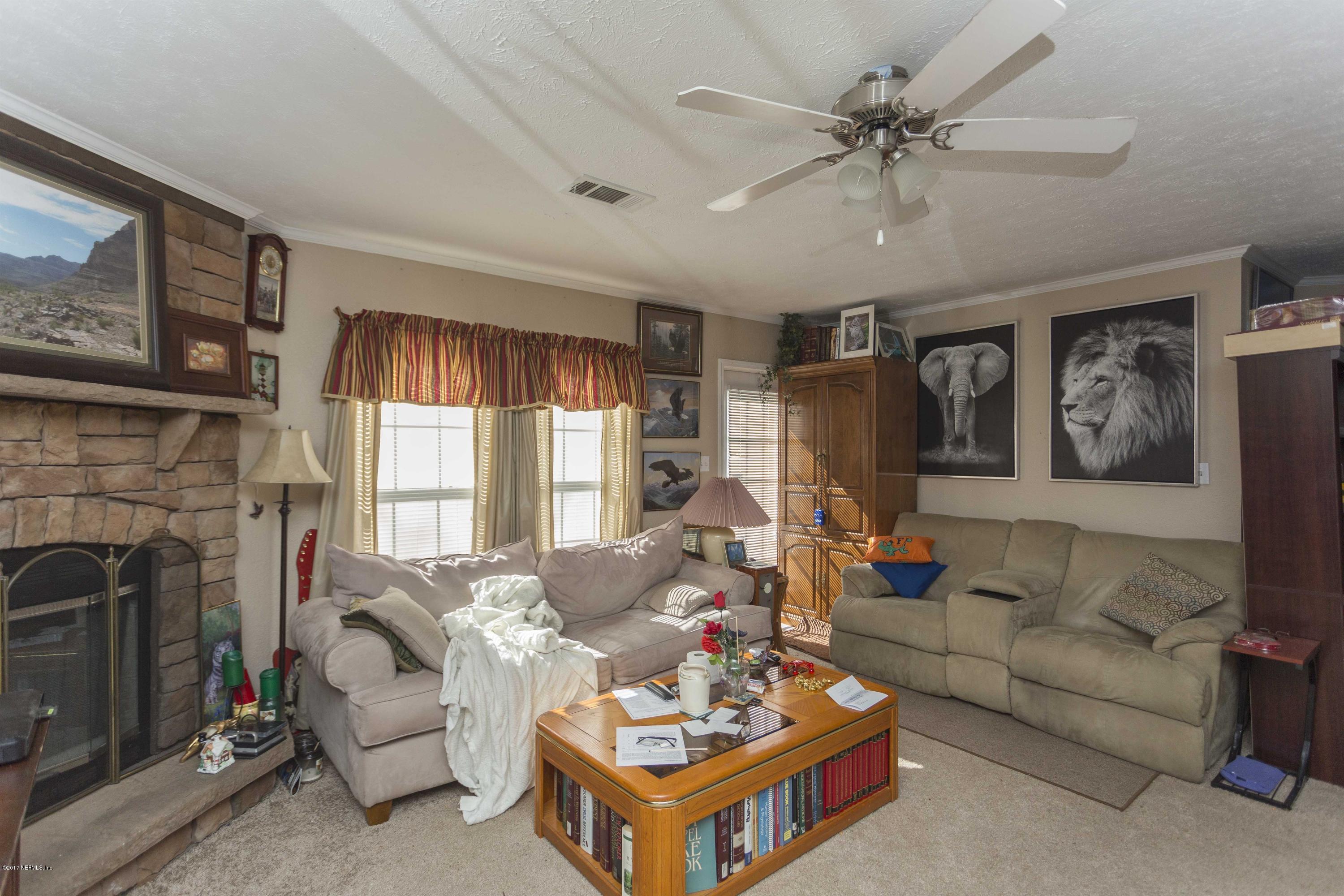 4049 Bronco Road Middleburg, FL 32068 - Photo 9 of 21 a living room with furniture a fireplace and a large window