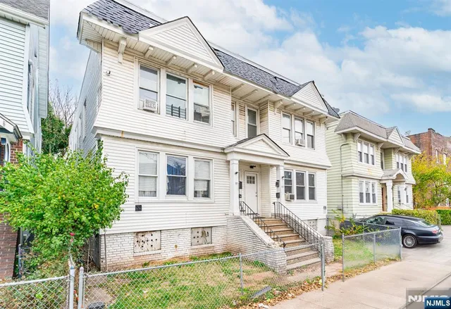 a view of a white building among the street with palm trees