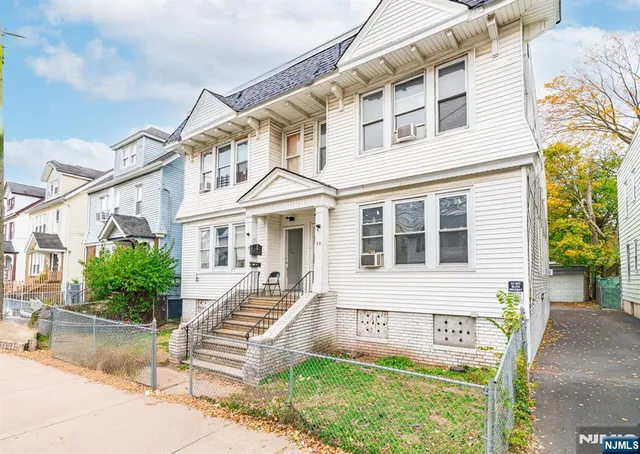 a front view of a building with a garden and plants