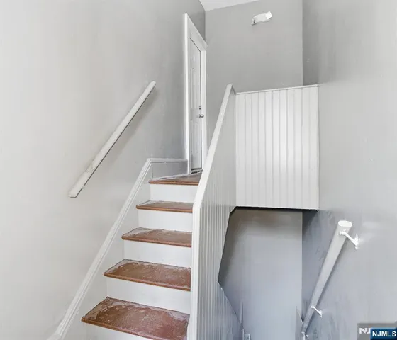 a view of staircase with wooden floor and white walls