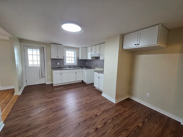 a kitchen with wooden floors and white cabinets