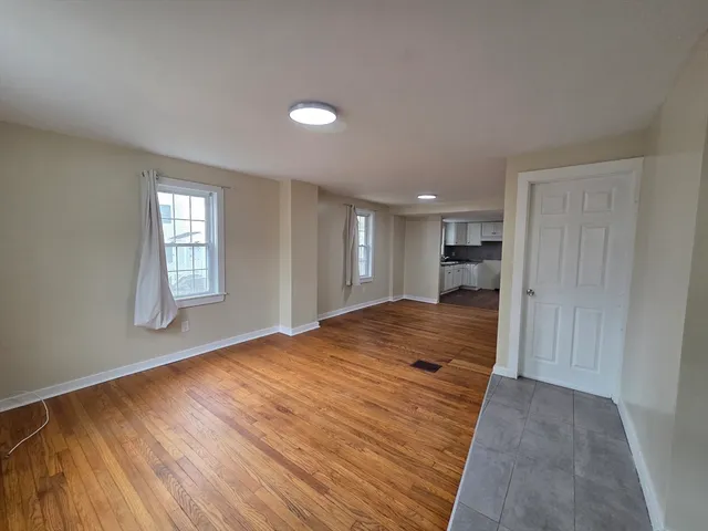 a view of empty room with wooden floor and window