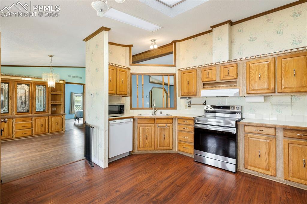 13335 Gymkhana Road Peyton, CO 80831 - Photo 22 of 38 Kitchen featuring wood-finish flooring, wood cabinetry, white countertops, stainless steel range, and a built-in microwave