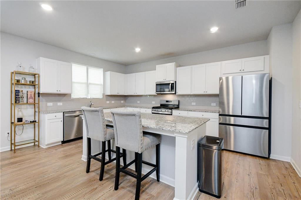 4774 Mock Orange Street Atlanta, GA 30331 - Photo 10 of 29 a kitchen with a refrigerator a stove a sink and white cabinets with wooden floor