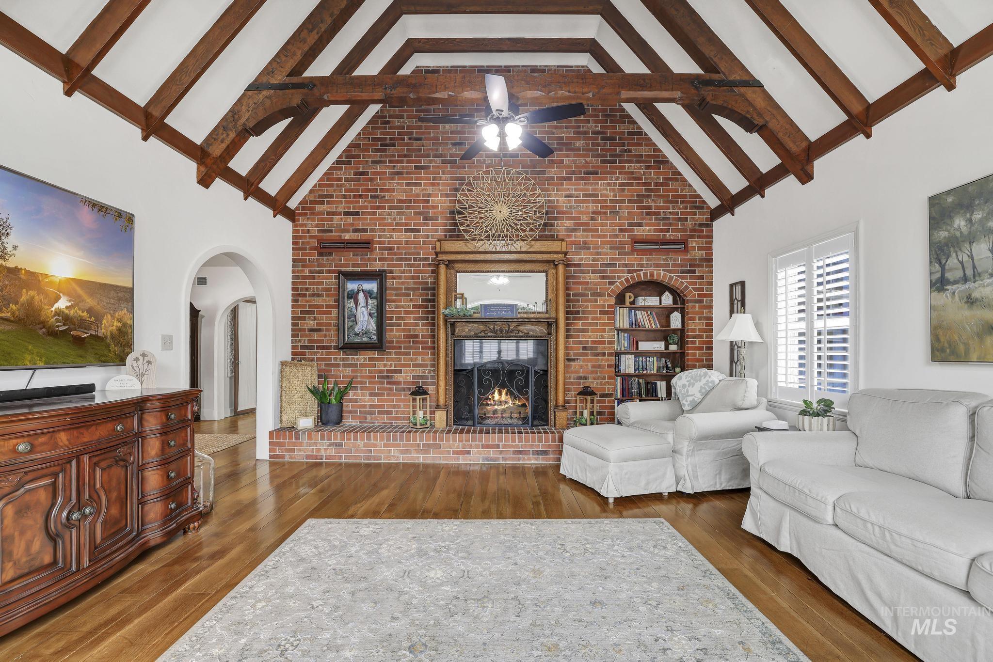 102 Fillmore Street Twin Falls, ID 83301 - Photo 12 of 48 Living area with a brick fireplace, dark wood-type flooring, a ceiling fan, and arched walkways