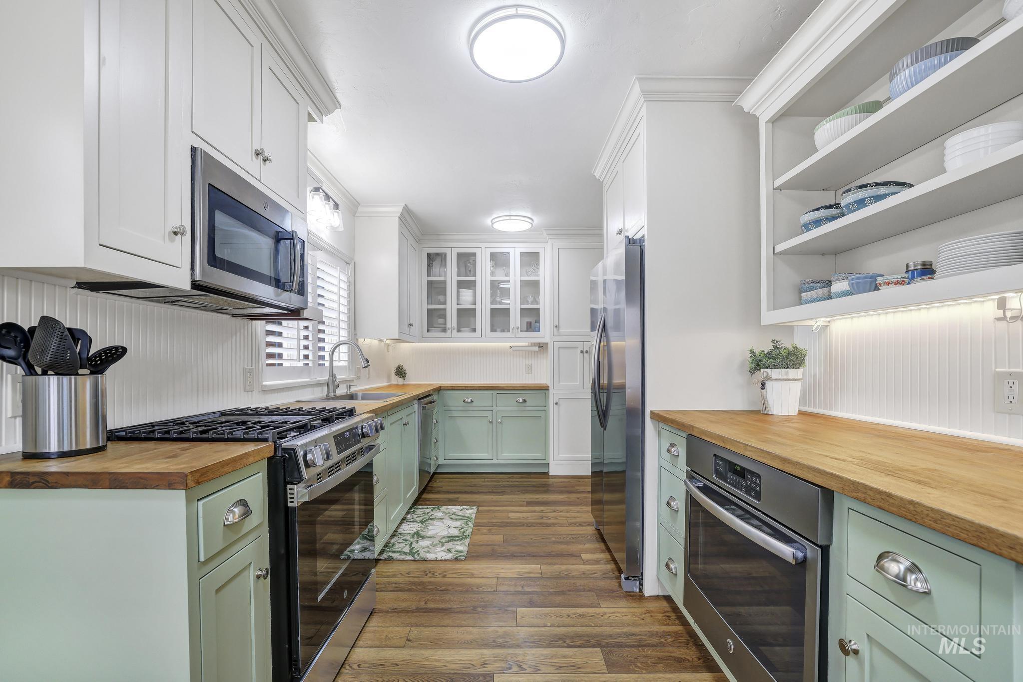 102 Fillmore Street Twin Falls, ID 83301 - Photo 15 of 48 Kitchen with butcher block countertops, stainless steel appliances, dual tone cabinetry, dark wood-style floors, and ornamental molding