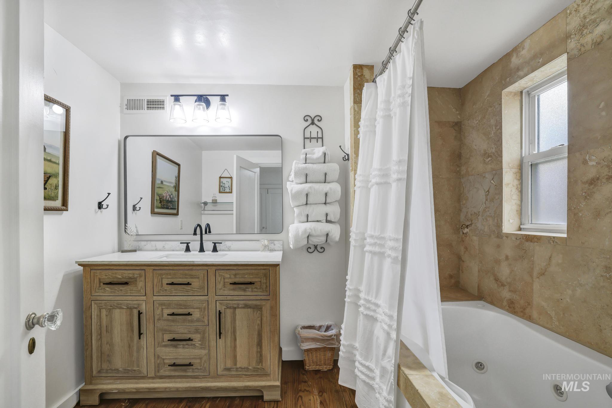 102 Fillmore Street Twin Falls, ID 83301 - Photo 31 of 48 Bathroom featuring vanity, a combined bath / shower with jetted tub, and dark wood-style flooring