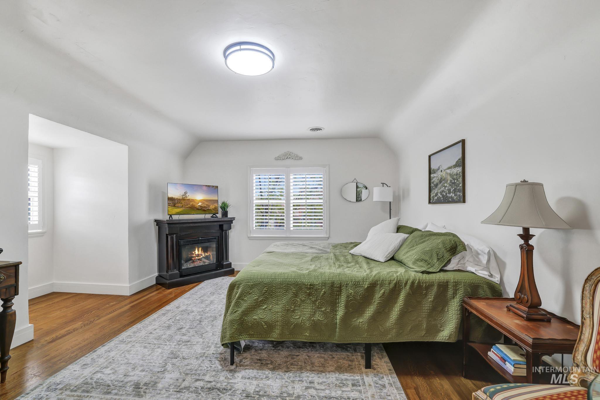 102 Fillmore Street Twin Falls, ID 83301 - Photo 32 of 48 Bedroom with vaulted ceiling, a glass covered fireplace, and dark wood-style floors