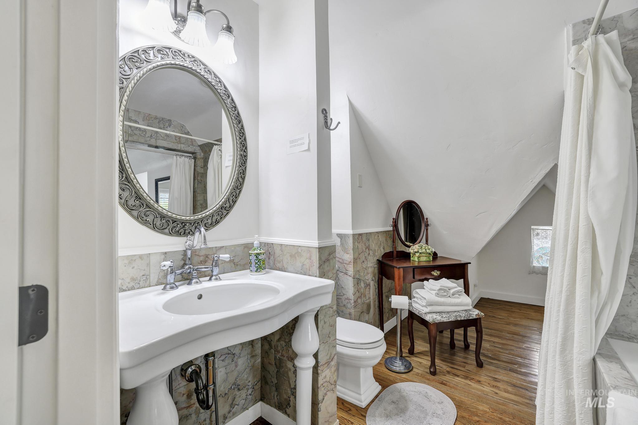 102 Fillmore Street Twin Falls, ID 83301 - Photo 35 of 48 Full bath featuring curtained shower, wood finished floors, tile walls, and vaulted ceiling