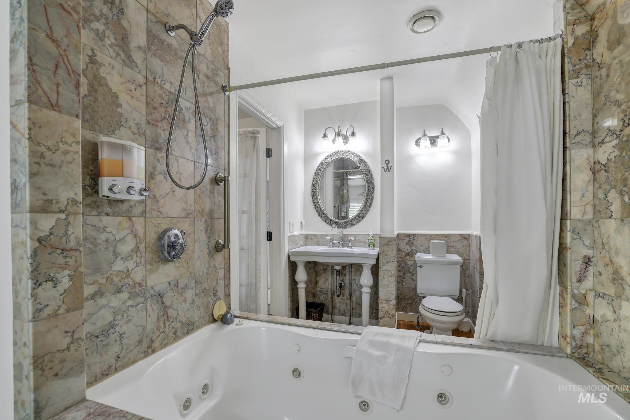 102 Fillmore Street Twin Falls, ID 83301 - Photo 37 of 48 Bathroom with tile walls, a combined bath / shower with jetted tub, and a wainscoted wall