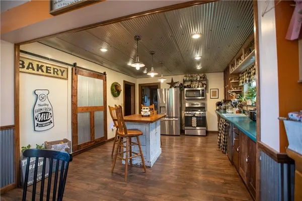 a kitchen with stainless steel appliances kitchen island granite countertop wooden floors and wooden cabinets