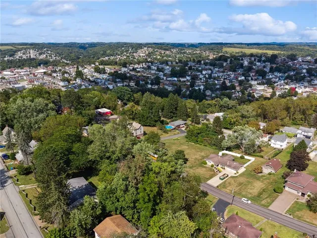 an aerial view of residential houses with outdoor space and trees