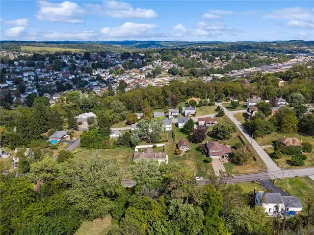 an aerial view of residential houses with outdoor space and trees